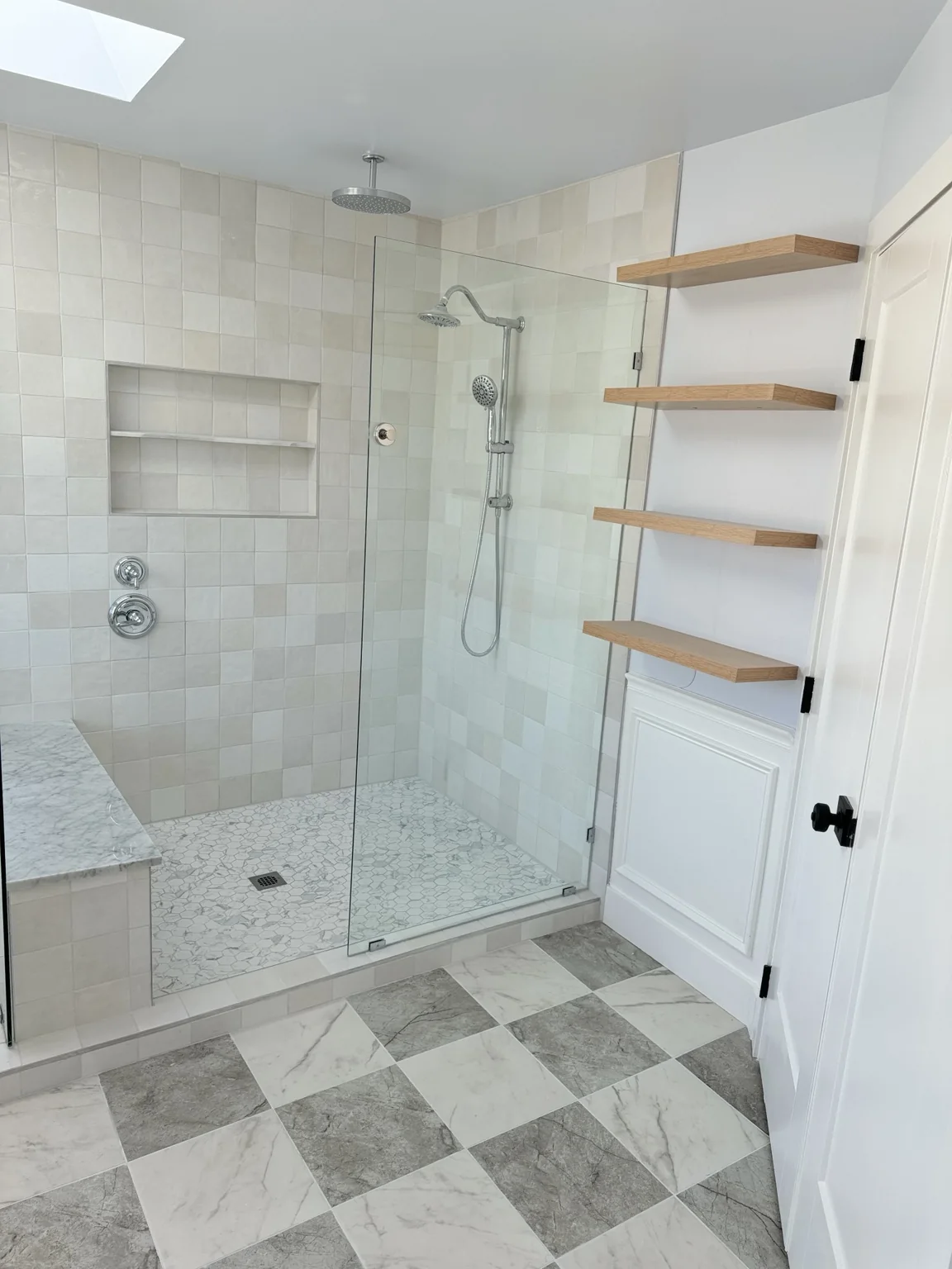 Walk in shower with patterned black and white floor tile
