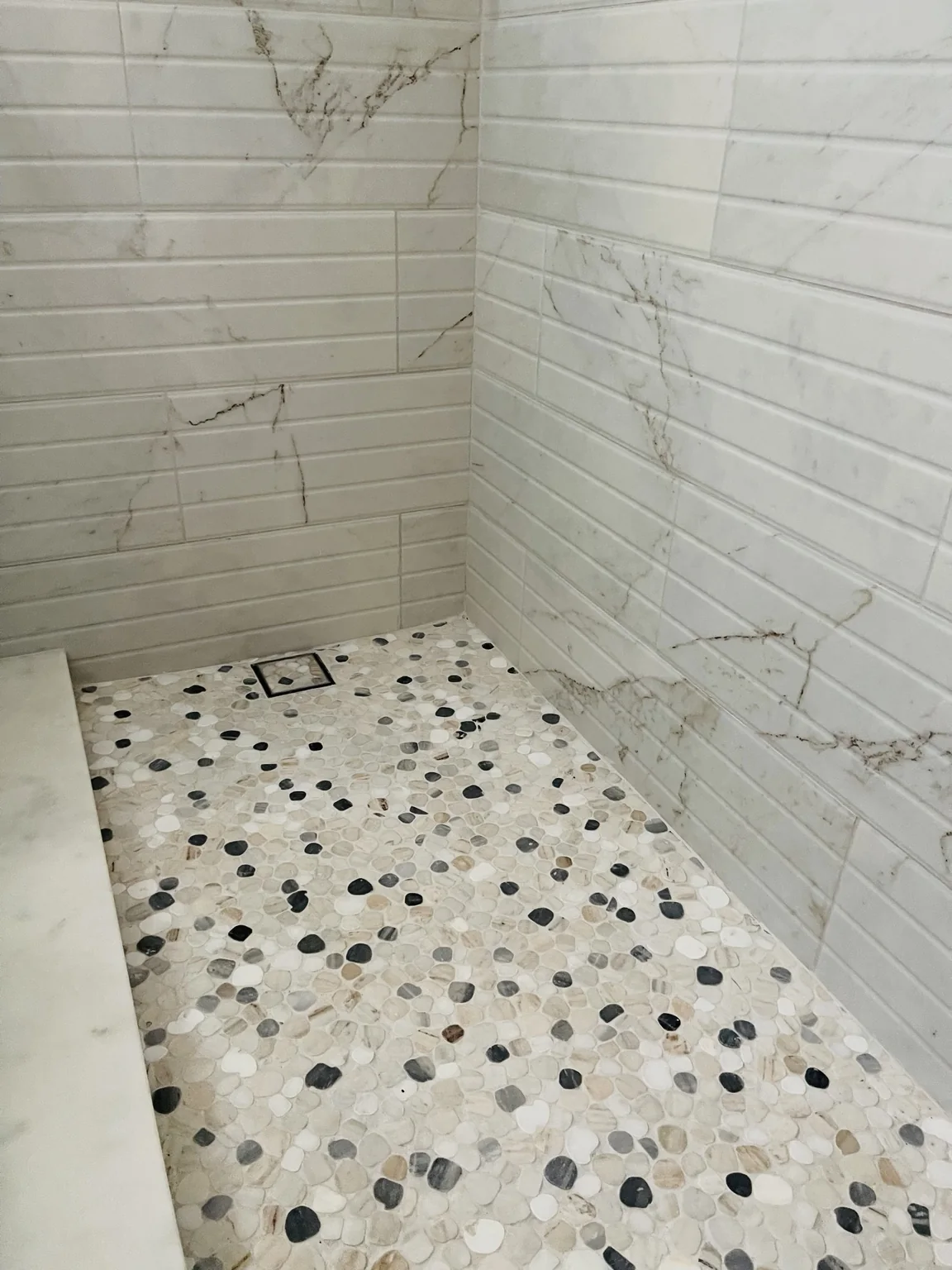 Walk in shower with pebble floor and teak bench